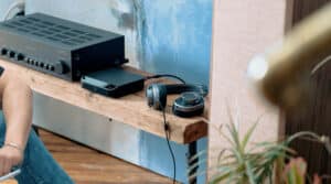 A close-up of a Bluesound streaming Node component on a shelf with a NAD integrated amplifier and a pair of headphones.