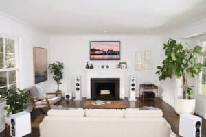 A living room with 6 white Bowers & Wilkins speakers in a surround sound setup.