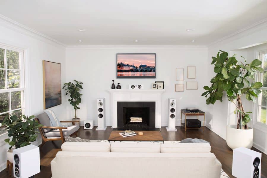 A living room with 6 white Bowers & Wilkins speakers in a surround sound setup.