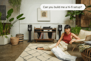 A woman next to a Bowers & Wilkins hi-fi speaker. Above the woman is a ChatGPT chat bubble that reads, ‘Can you build me a hi-fi setup?’