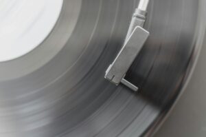 A black and white close-up of a turntable tonearm on a record.