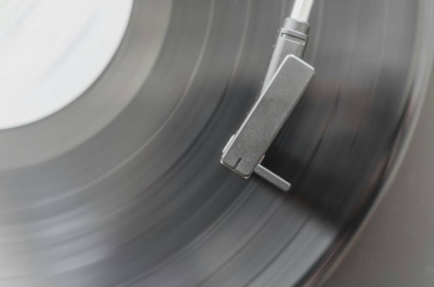 A black and white close-up of a turntable tonearm on a record.