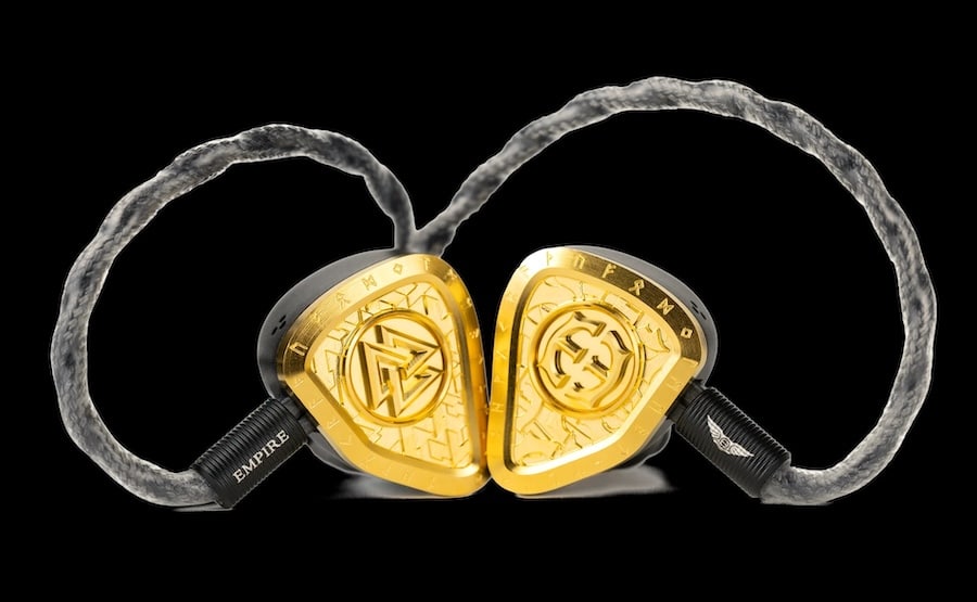A close-up view of Empire Ears high-end in-ear monitors with gold trim and braided cable.