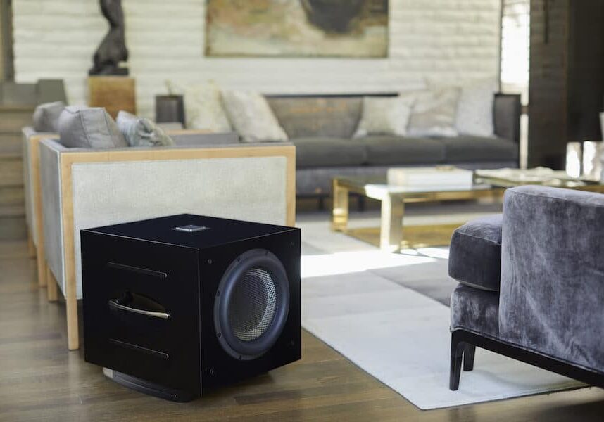 A black REL Acoustics subwoofer in a living room.
