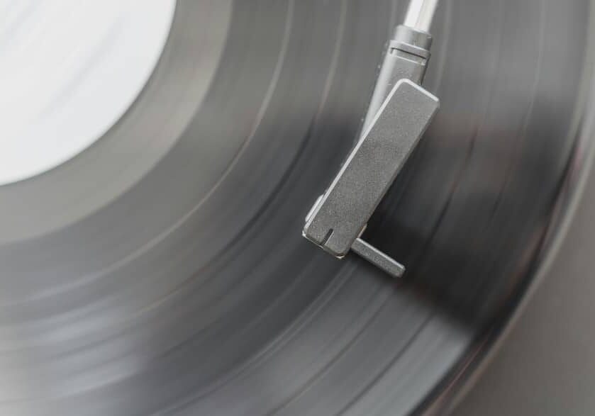 A black and white close-up of a turntable tonearm on a record.