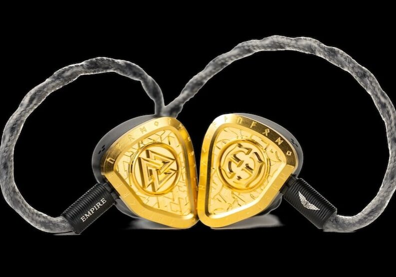 A close-up view of Empire Ears high-end in-ear monitors with gold trim and braided cable.