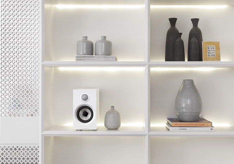 A Bowers & Wilkins bookshelf speaker in a white cabinet. Vases are in the other cabinet compartments.