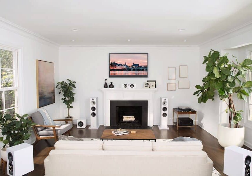 A living room with 6 white Bowers & Wilkins speakers in a surround sound setup.