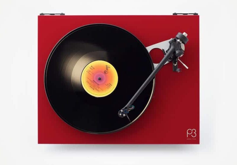 A red Rega turntable on a white background.